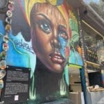 Colorful street art mural in Comuna 13 Medellín showing a woman's face with vibrant colors and deep artistic meaning.