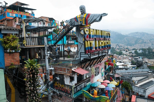Group of street dancers performing breakdance in Comuna 13 Medellín, surrounded by colorful murals, international flags, and vibrant street culture.